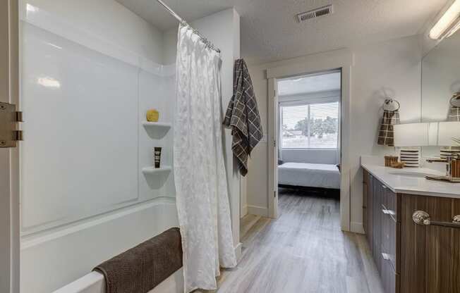 Bathroom with garden tub, wood tone floor, and open door leading to attached bedroom