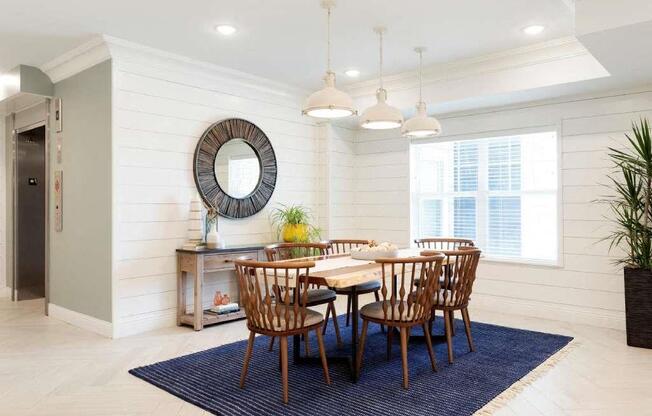 A dining room with a round mirror and a wooden table.