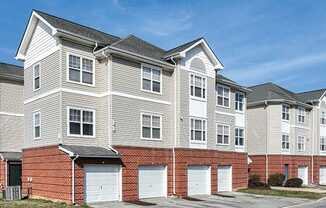 A large, multi-story residential building with a brick base and white upper floors.