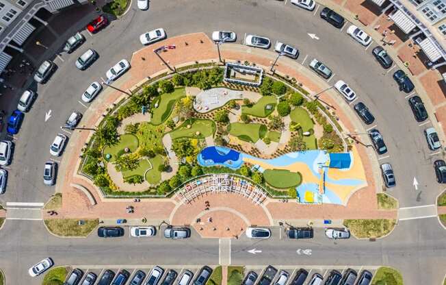 An aerial view of a roundabout with a park in the middle.