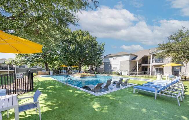 A pool area with sun loungers and a yellow umbrella.