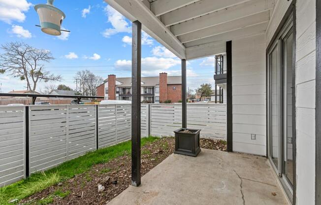 A white house with a porch and a grey fence.