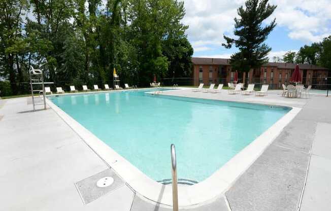 A large swimming pool surrounded by trees and chairs.