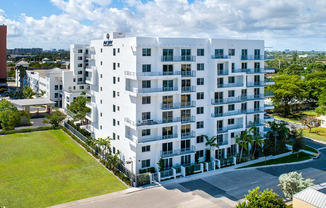 an aerial view of a white apartment building with grass and trees at Saba Pompano Beach, Pompano Beach, 33062