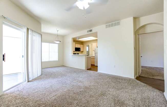 A living room with a carpet floor and a ceiling fan.