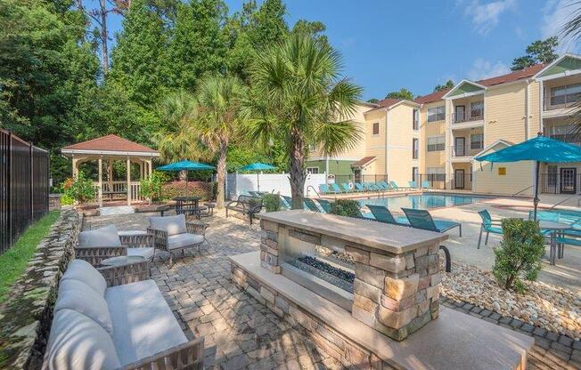 Cozy fire pit near pool with fireplace and several large lounging chairs at Evergreens at Mahan apartments in Tallahassee, FL