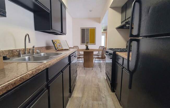 a kitchen with black appliances and counters and a dining room with a table