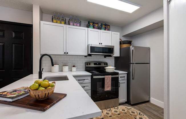 A kitchen with white countertops and a black refrigerator.
