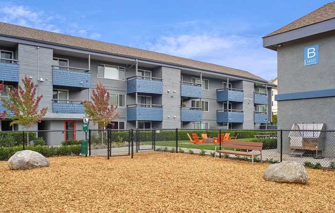 Dog run with enclosed fence outside exterior of building. Wood chips fill the dog area. at 3030 Lake City, Seattle, Washington