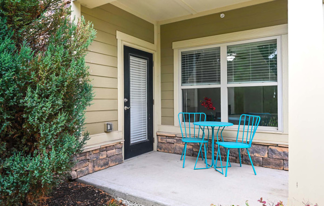 a patio with blue chairs and a table and a door at Sovereign at Overland Park, Overland Park Kansas  