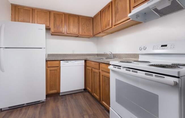 an empty kitchen with white appliances and wooden cabinets