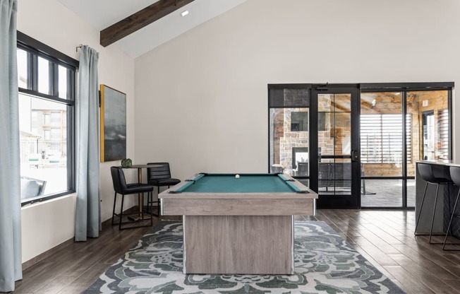 a pool table in a living room with a view of a patio