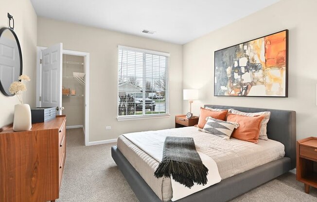 furnished bedroom with wall art, a walk-in closet, and a large window in a Farmington Lakes home