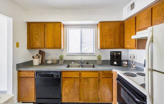 A kitchen with wooden cabinets and a black dishwasher.