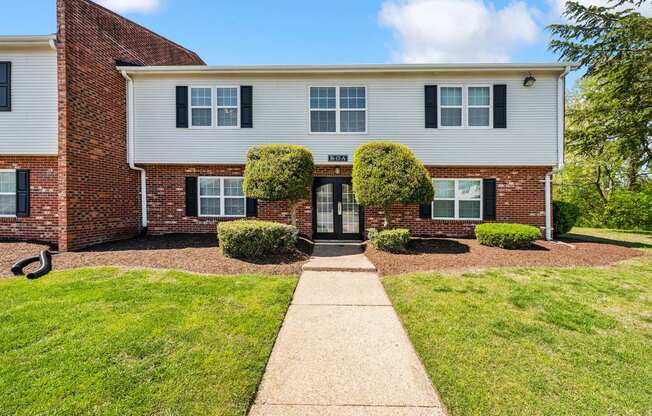 A white and brick building with a green lawn in front.