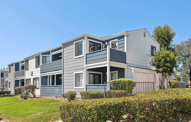 A grey and white building with a green lawn in front.