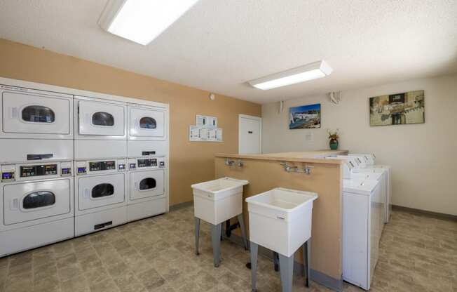 a laundry room with washers and dryers and a counter with sinks at Campbell West Apartments, Campbell, CA