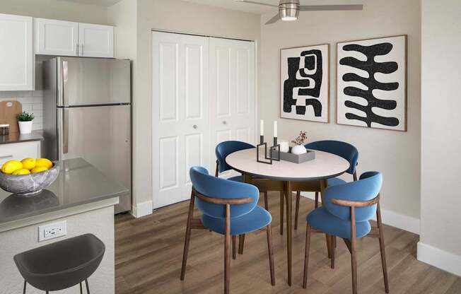 A modern kitchen with a round table and blue chairs.