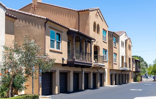 A row of tan buildings with balconies and blue windows.