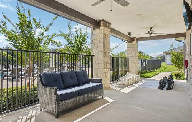 A black sofa sits on a patio under a white awning.
