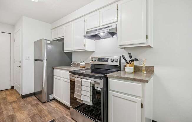 A kitchen with white cabinets and a stainless steel refrigerator.