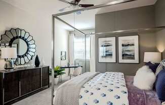 Bedroom with canopy bed, dark dresser, and decorative mirror accent
