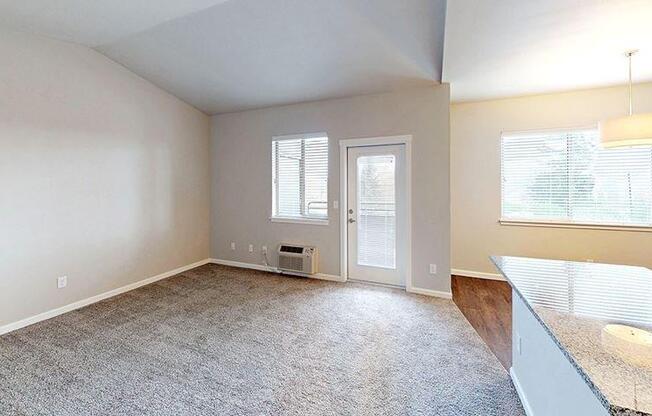 an empty living room with a kitchen and a door