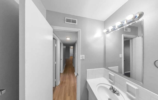 a bathroom with a sink and a mirror and a hallway