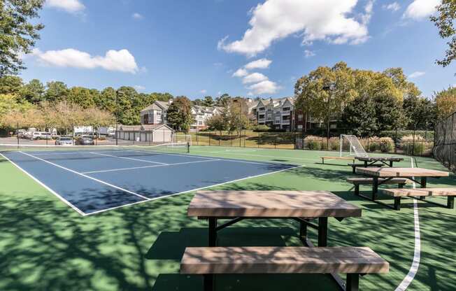 a tennis court with picnic tables in front of a basketball court at Roswell Village, Roswell, Georgia