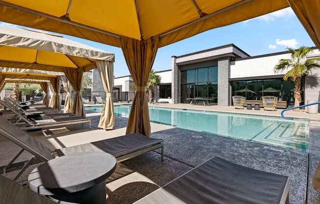 a pool with lounge chairs and umbrellas next to a building