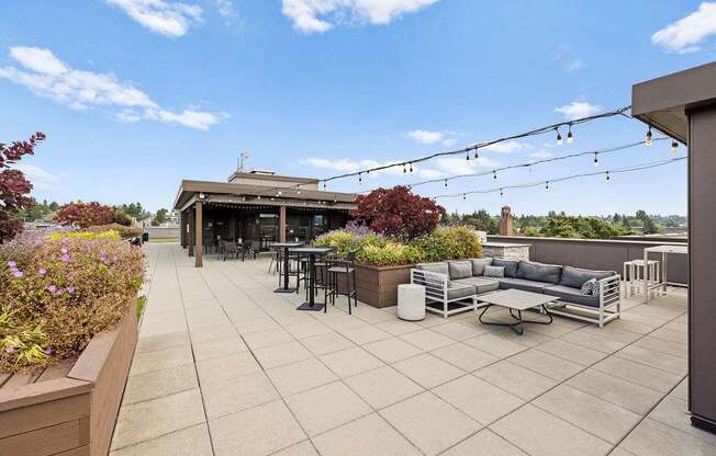 A patio with a table and chairs is surrounded by plants.