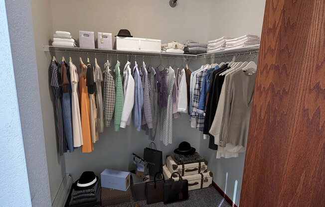 a walk in closet with a rack of clothes and shoes on the floor