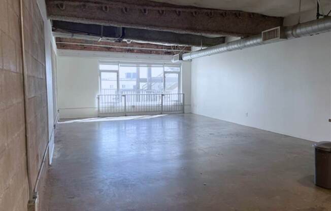 A large empty room with a window and a balcony.