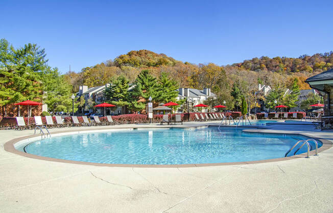 a resort pool with chairs and umbrellas on a sunny day