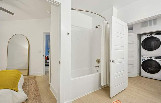 a bathroom with a washer and dryer and a door to a laundry room at Link Apartments® Calyx, Chapel Hill