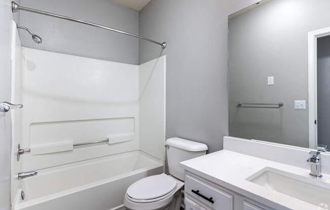 A white bathroom with a toilet, sink, and bathtub.