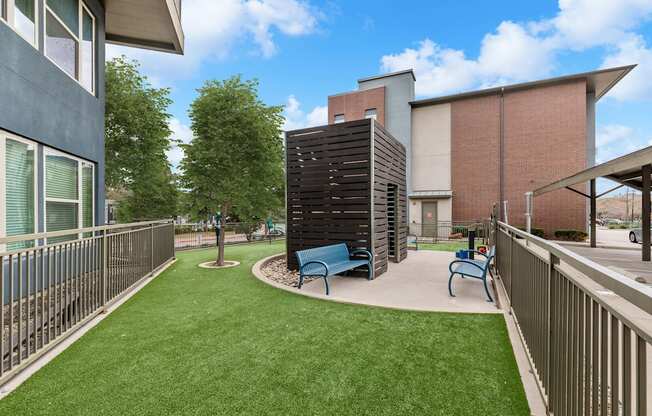 A small grassy area with a bench and a tall black structure.
