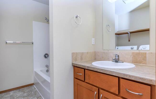 A bathroom with a sink, mirror, and bathtub.