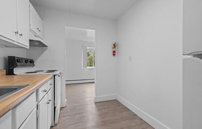 a kitchen with white cabinets and white appliances and a window