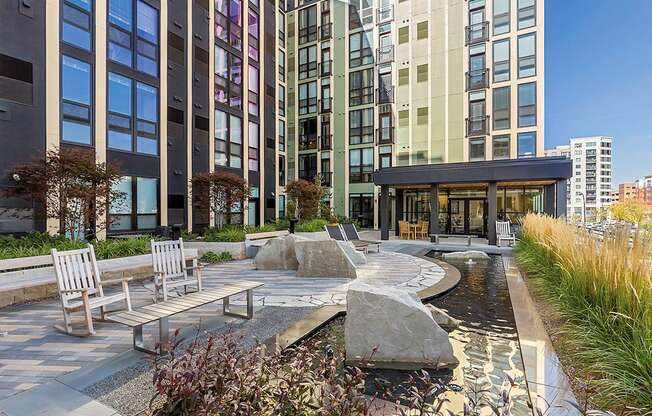 a courtyard with benches and a water feature in front of a tall building at Ann Arbor City Club, Michigan, 48104