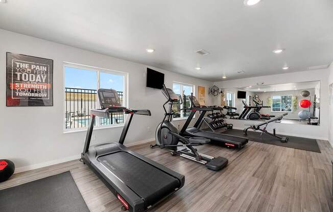 A gym with treadmills, elliptical machines, and a poster on the wall.