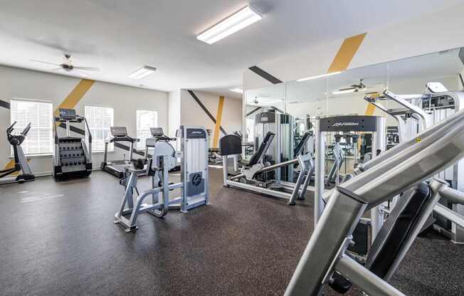 A gym with a variety of equipment including treadmills, weights, and exercise machines.