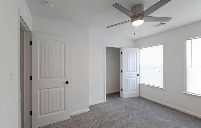 Carpeted bedroom with ceiling fan and closet