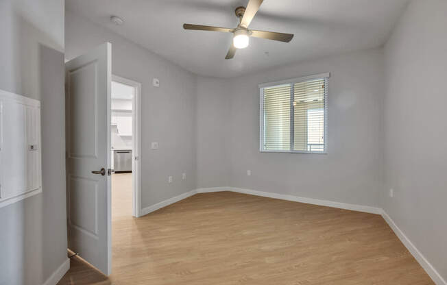 A room with a ceiling fan and a window with blinds.