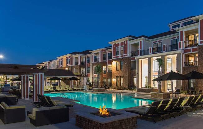 a swimming pool is lit up at night in front of an apartment building at Nexus at Sandhill, Columbia, SC 29229
