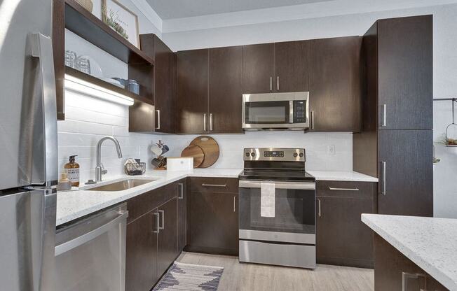 A modern kitchen with dark brown cabinets and stainless steel appliances.