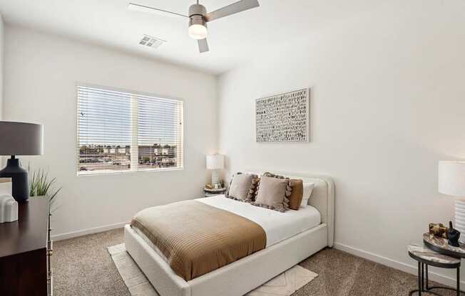 A bedroom with a bed, nightstands, and a ceiling fan.