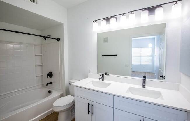 Colton Apartments bathroom with white double sinks and tub