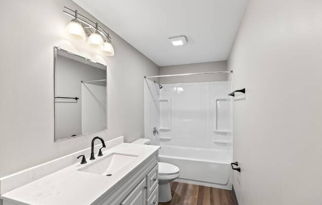 A white bathroom with a sink, mirror, and toilet.