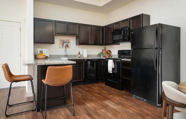 A kitchen with black cabinets and a black fridge.